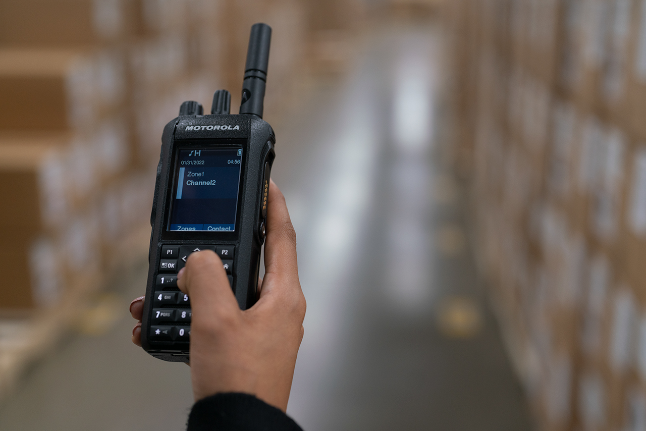 person holding Motorola radio to communicate with underground team